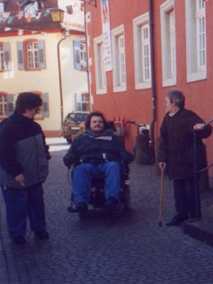 Personen mit Rollstuhl und Gehstock bei einer Ortsbegehung